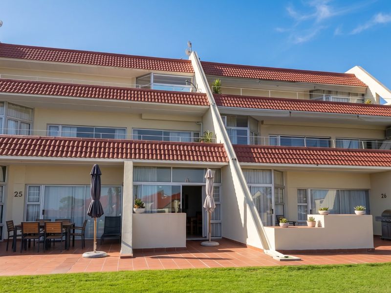 Rear elevation of a multi-story apartment complex featuring private ground-floor patios with tiled flooring and sliding door access to the living areas.