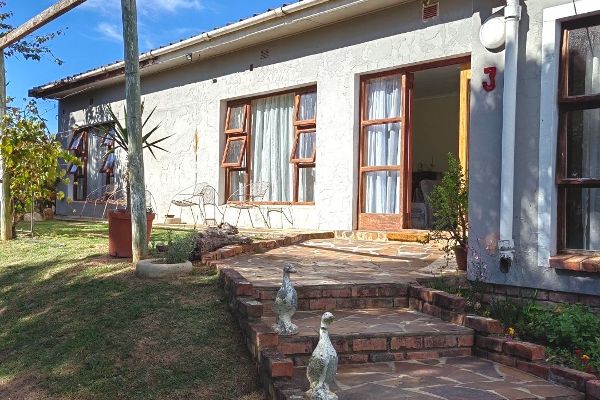 Rear exterior view of the house featuring a stone paved patio, brick steps, and timber framed windows and doors.