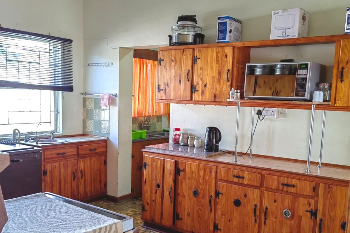 A dated kitchen featuring timber cabinetry, laminate countertops, and a tiled splashback, offering significant potential for a modern renovation.