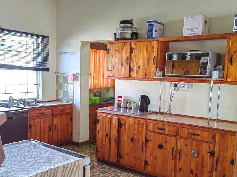 A dated kitchen featuring timber cabinetry, laminate countertops, and a tiled splashback, offering significant potential for a modern renovation.