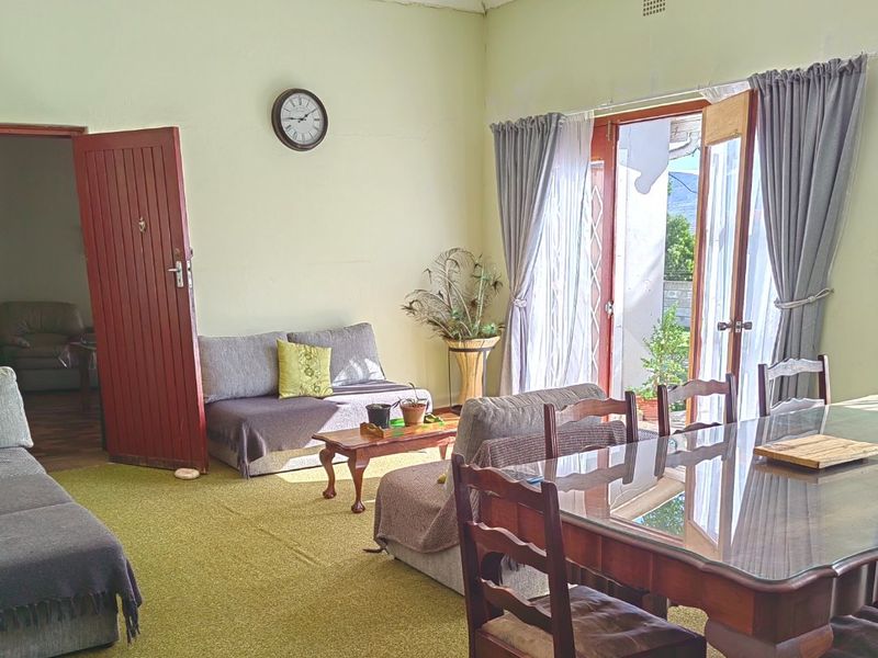 Open plan living and dining area featuring carpet flooring, direct access to the patio through double glass doors, and traditional timber door entry.