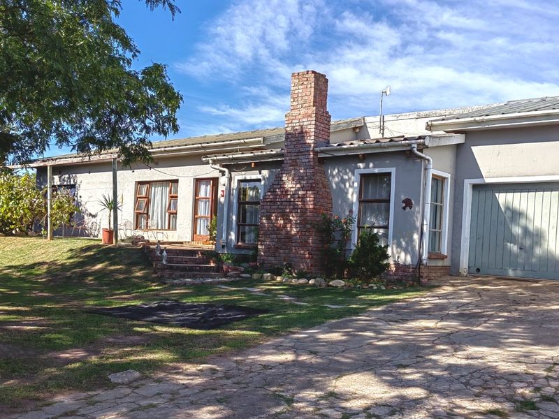 Front elevation of a single-story house featuring a prominent brick chimney, paved driveway, and attached garage.