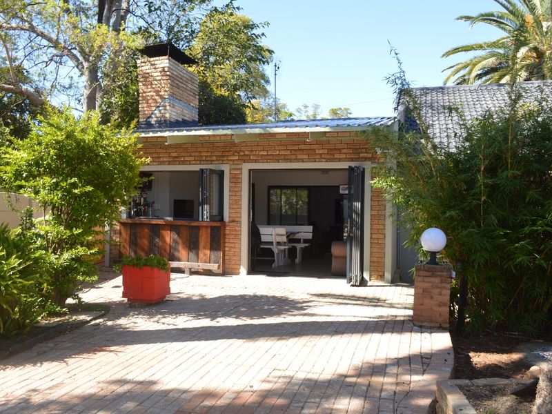 Outdoor entertainment area featuring a brick structure with a built-in bar, chimney, and folding doors opening onto a paved patio.