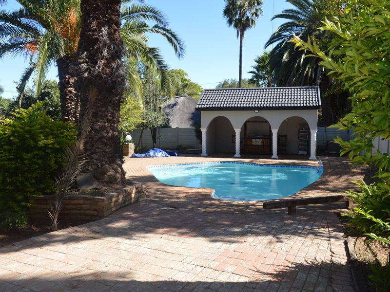 Outdoor pool area featuring a swimming pool, brick paved surround, and a covered patio structure with arched columns.