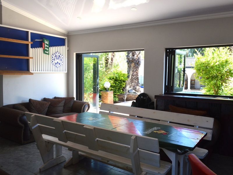 An indoor entertainment area featuring bi-fold doors opening to the garden, tiled flooring, and a built-in bar counter.
