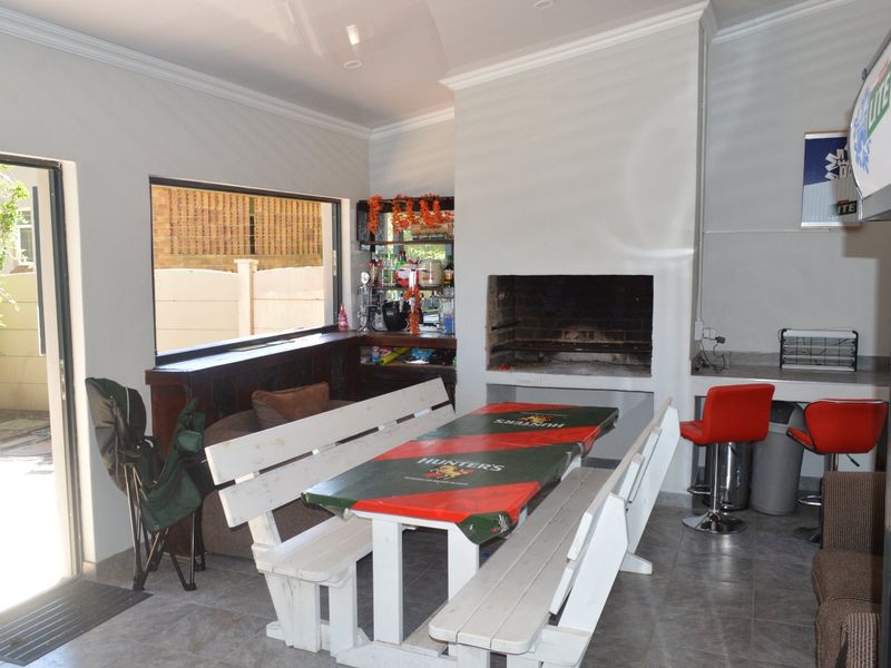 Covered entertainment area featuring a built-in braai, integrated bar counter, and tiled flooring, providing a functional space for outdoor dining and social gatherings.