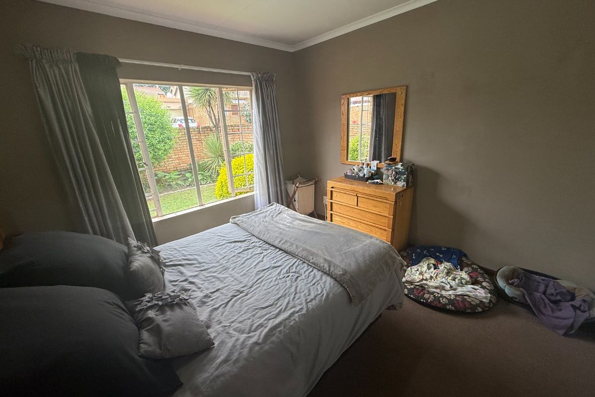 A standard bedroom featuring carpeted flooring, a large window providing natural light, and neutral wall finishes.