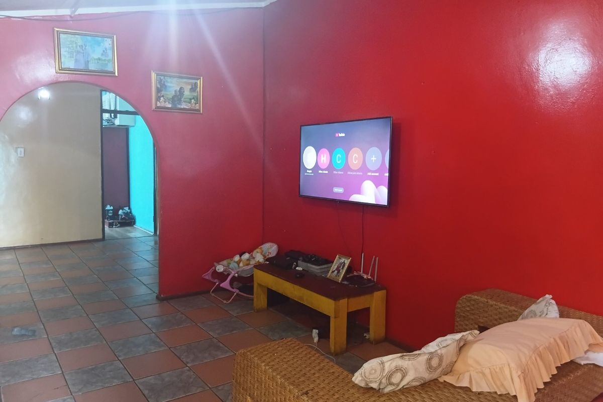 A living room featuring tiled flooring and an arched entryway, currently finished with bold red wall paint.