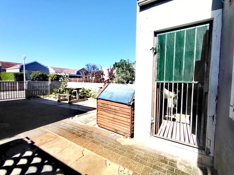 Rear exterior area featuring paved patio space, boundary wall, and a secure gated entrance to the property.