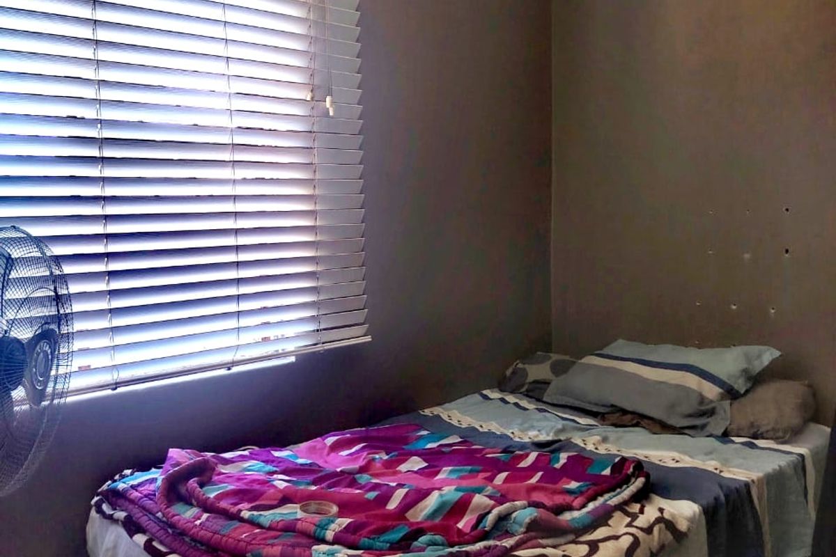 A compact bedroom featuring dark painted walls, coving, and venetian blinds. The room shows signs of wall surface wear.