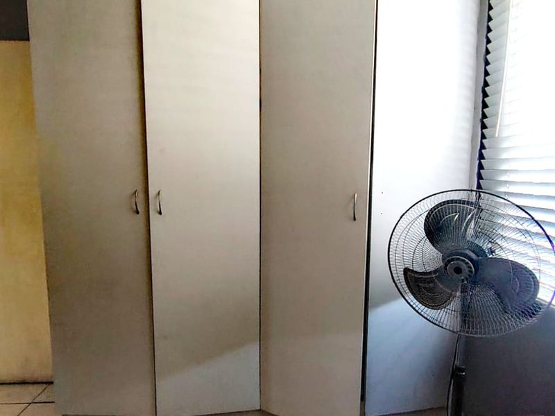 A bedroom featuring built-in wardrobes with misaligned doors and tiled flooring, requiring cosmetic updates to improve the overall aesthetic.