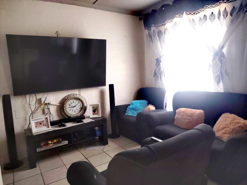 A living room featuring tiled flooring and a wall-mounted television setup.