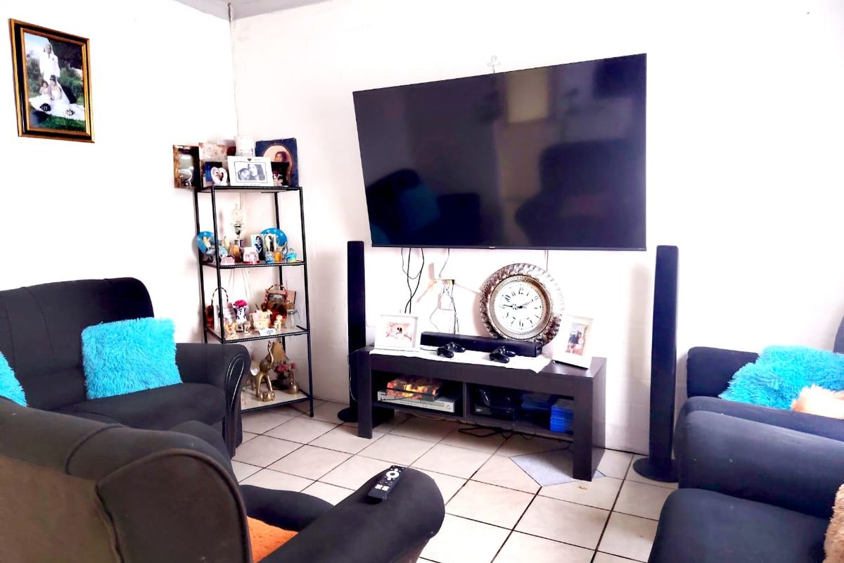 A living room featuring ceramic floor tiles and a wall-mounted television setup.