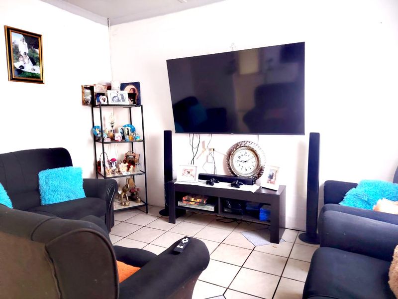 A living room featuring ceramic floor tiles and a wall-mounted television setup.