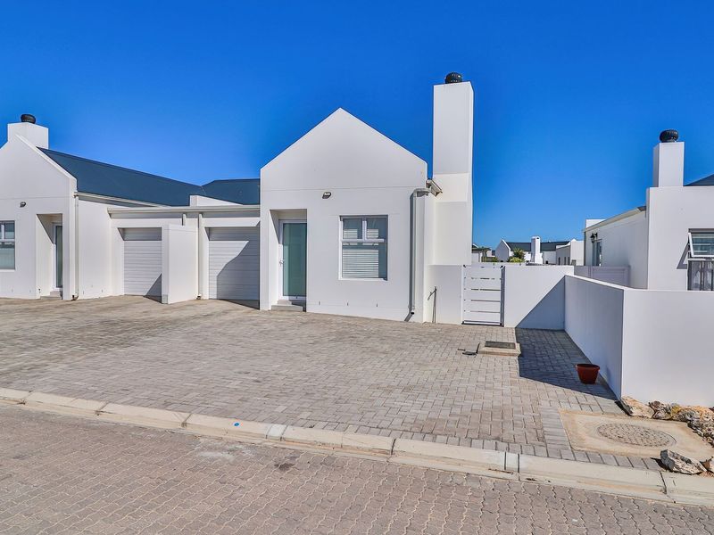Front exterior view of a modern townhouse featuring a paved driveway, double garage, and clean white facade with a prominent chimney.