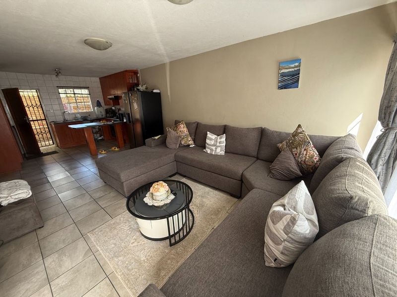 Open-plan living area featuring tiled flooring and a functional kitchen with built-in cabinetry, providing a practical layout for daily living.