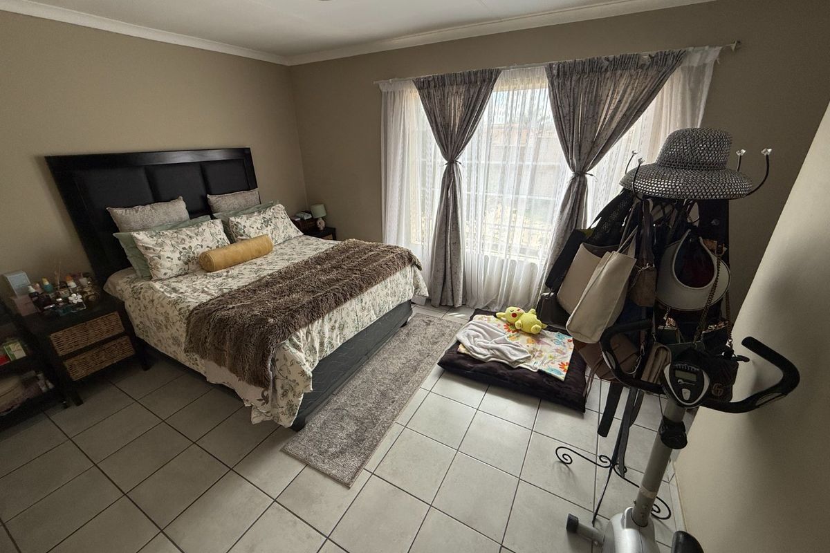 A functional bedroom featuring tiled flooring and large windows with curtain tracks, providing a neutral base for personal styling.