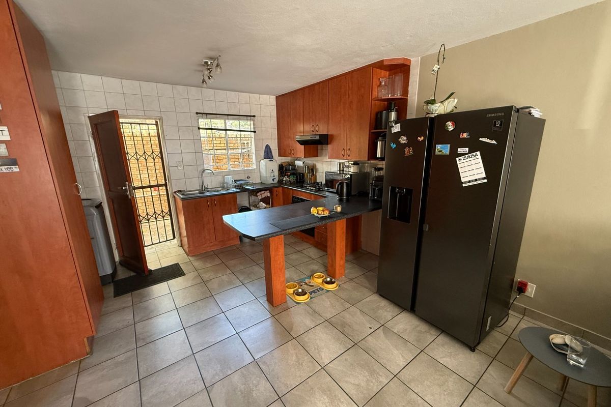 Functional kitchen featuring wooden cabinetry, a breakfast bar, tiled flooring, and direct access to an exterior security gate.