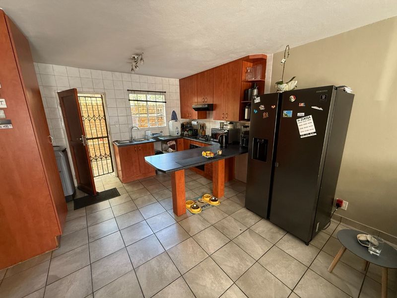 Functional kitchen featuring wooden cabinetry, a breakfast bar, tiled flooring, and direct access to an exterior security gate.
