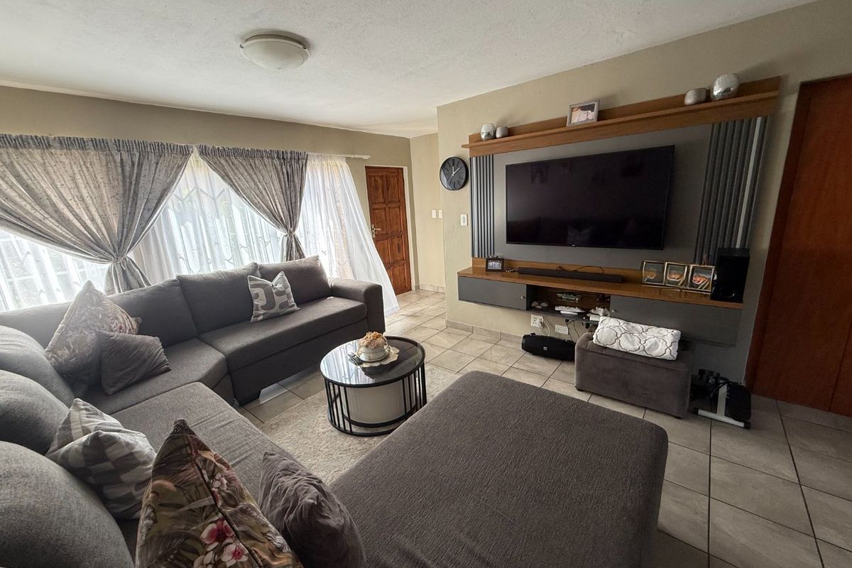 A comfortable living room featuring tiled flooring and a custom built-in media wall unit, providing a functional and well-maintained space.