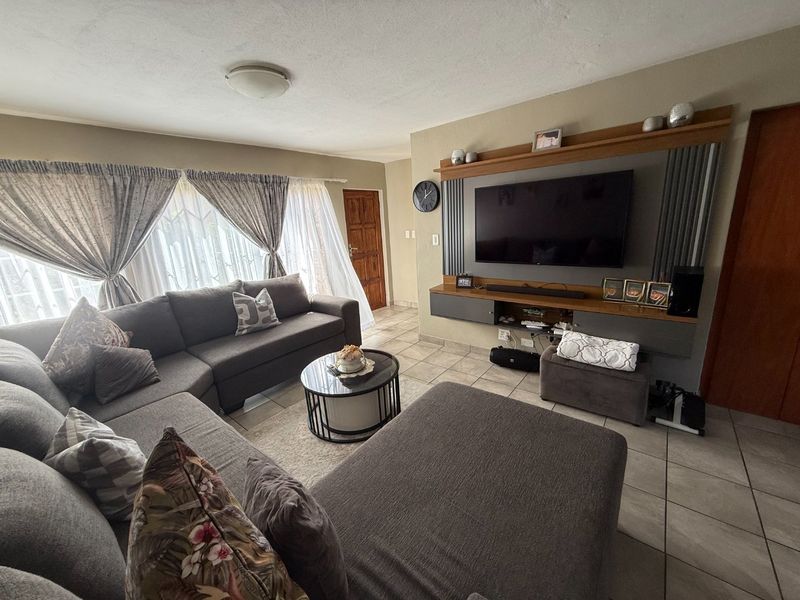 A comfortable living room featuring tiled flooring and a custom built-in media wall unit, providing a functional and well-maintained space.
