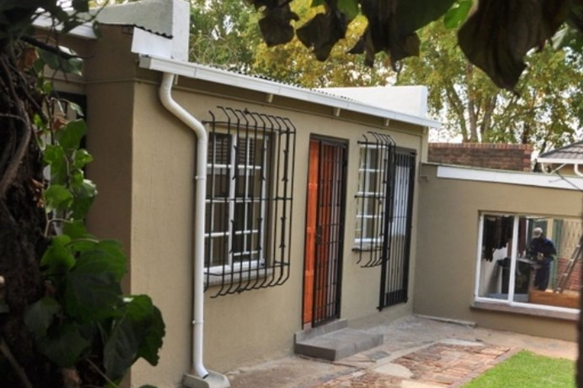 Rear exterior view of the property featuring security bars on windows, a security gate, and a brick pathway leading to the entrance.