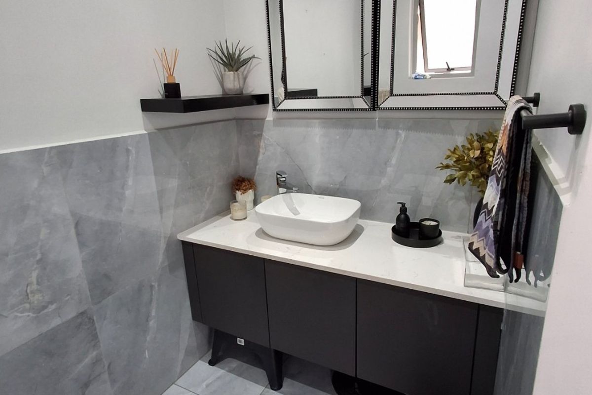 Modern bathroom featuring a floating vanity with a vessel sink, stone countertop, and contemporary large-format grey tiling.