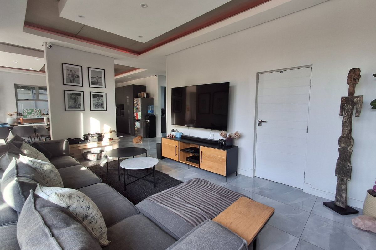 A modern living room featuring tiled flooring, a recessed ceiling with integrated lighting, and a clean, neutral aesthetic.