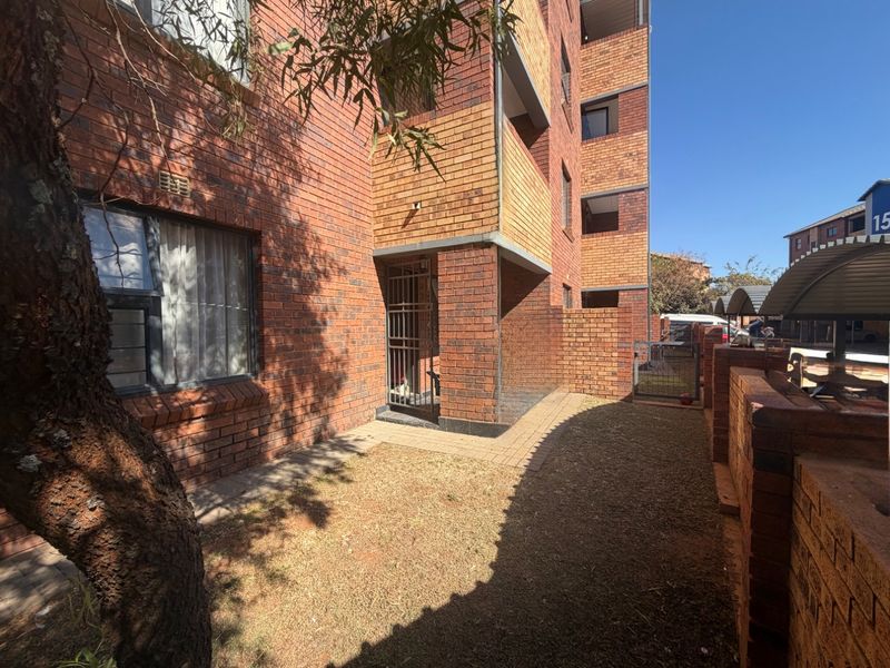 Ground floor apartment exterior featuring a private brick-walled garden area, paved walkway, and secure gated entrance.