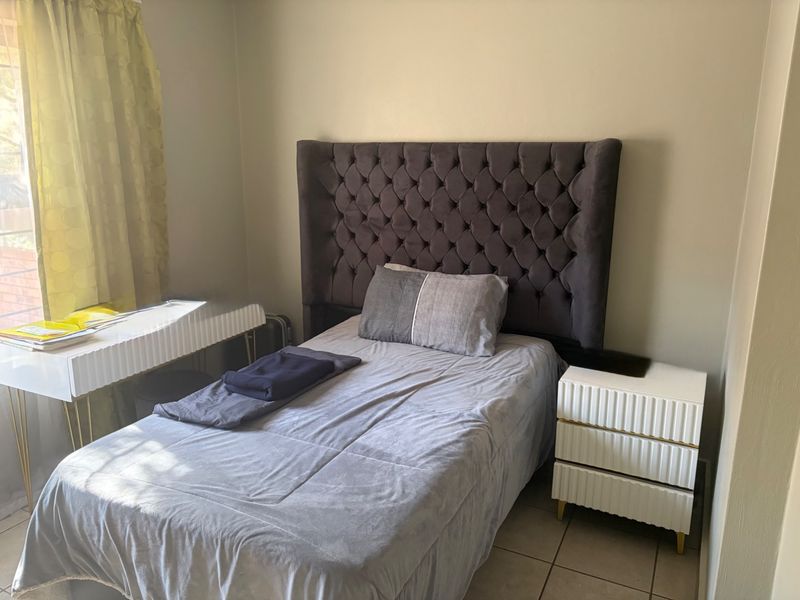 A compact bedroom featuring tiled flooring and neutral wall finishes, providing a functional space for rest.