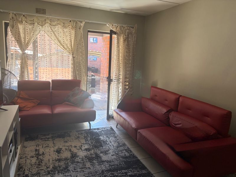 A living room area featuring tiled flooring and a glass door providing access to the exterior.