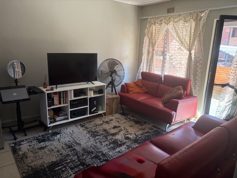 A functional living room featuring tiled flooring and a sliding glass door providing access to the exterior.