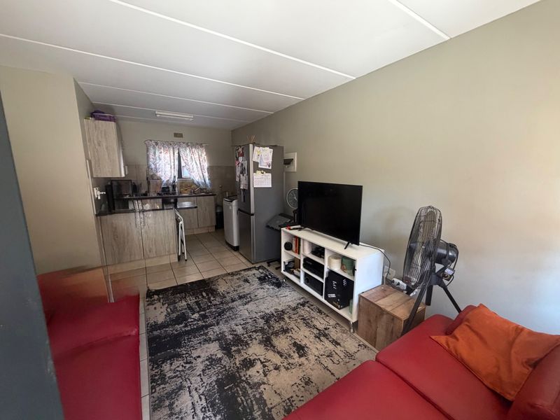 Open plan living area featuring a compact kitchen with built-in cabinetry and tiled flooring, seamlessly connected to the main living space.