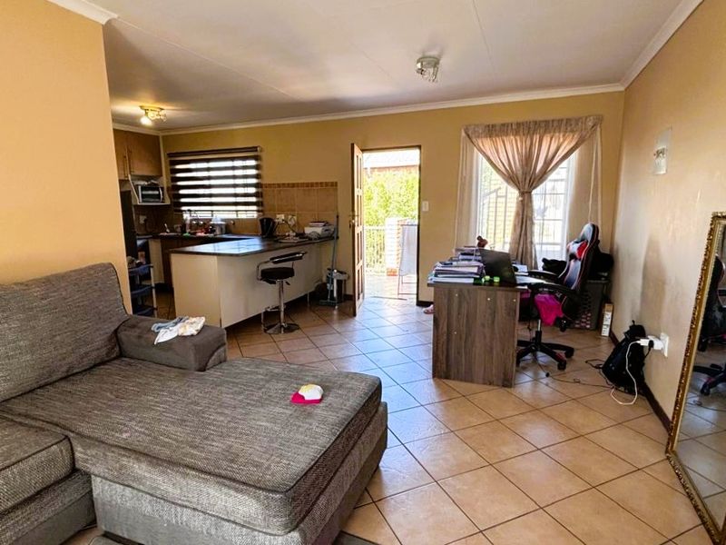 Open plan living area featuring tiled flooring, a kitchen with breakfast bar, and direct access to an outdoor space.