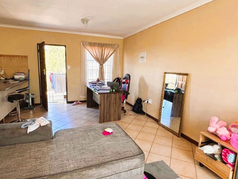 Open-plan living area featuring tiled flooring and an integrated kitchen with breakfast bar, providing a functional and versatile space for daily living.