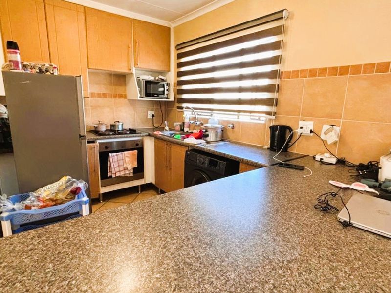 Functional kitchen featuring laminate cabinetry, granite countertops, built-in oven, hob, and tiled backsplash with a convenient breakfast bar area.