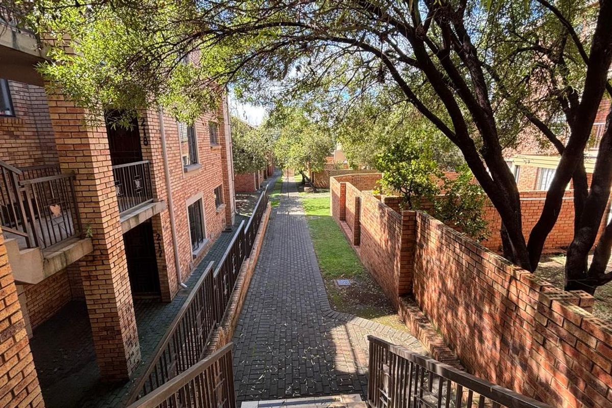 Exterior view of the apartment complex featuring brick facades, paved walkways, and established landscaping between the residential blocks.