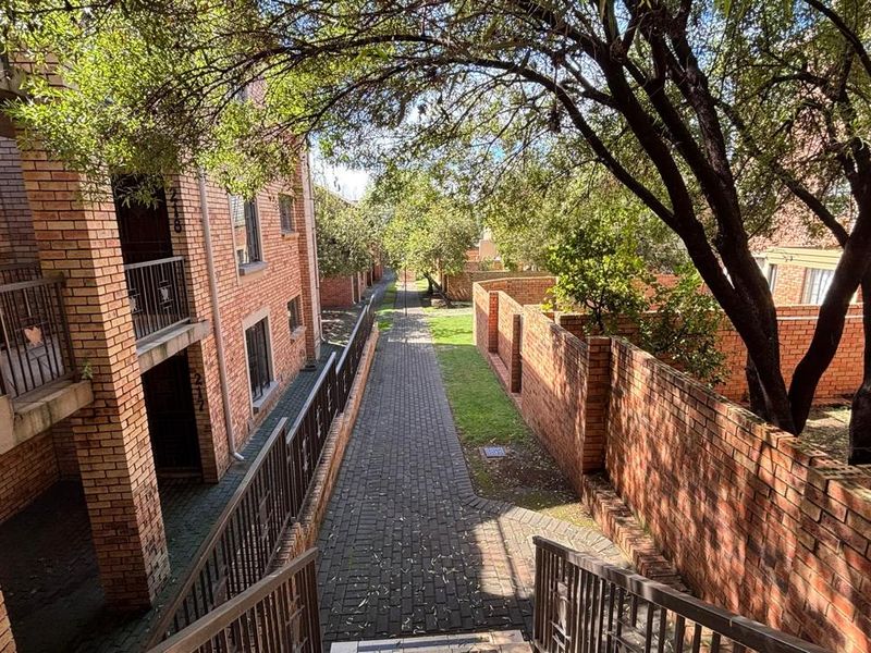 Exterior view of the apartment complex featuring brick facades, paved walkways, and established landscaping between the residential blocks.