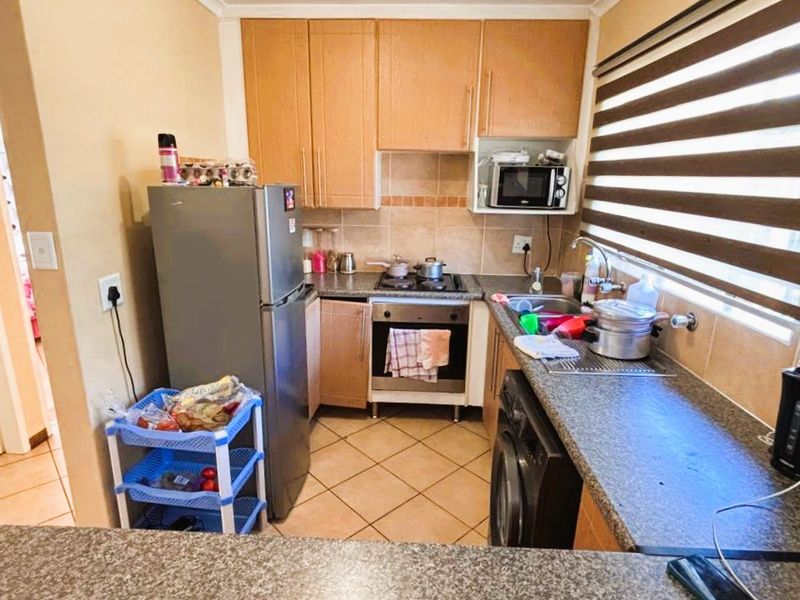 A functional kitchen featuring built-in cabinetry, laminate countertops, a built-in oven and hob, and tiled flooring with a tiled backsplash.