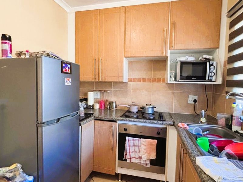 Compact kitchen featuring light wood cabinetry, granite countertops, a built-in oven with hob, and a tiled backsplash.