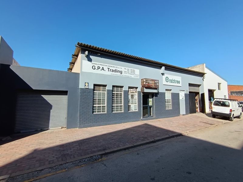 Commercial street-front property featuring a brick facade, roller shutter garage door, and secure window grilles, suitable for retail or industrial use.