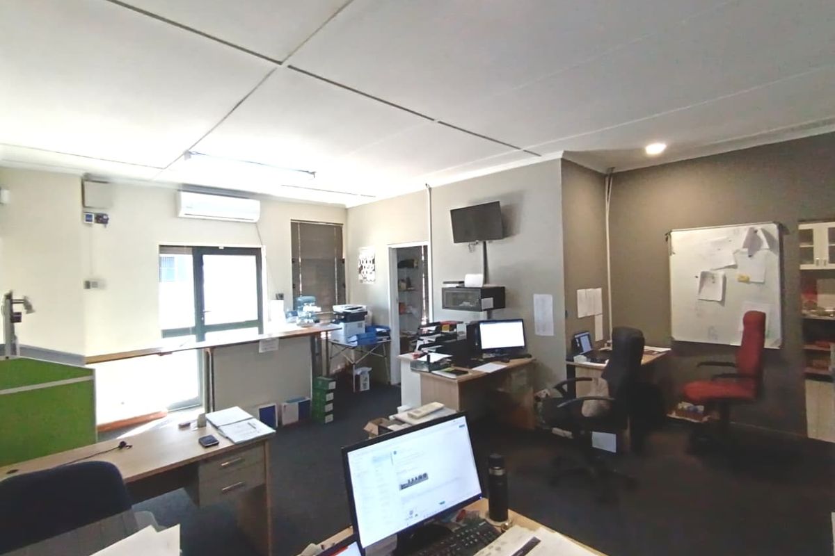A functional commercial office space featuring a suspended ceiling, split-system air conditioning, and carpeted flooring, suitable for a professional work environment.