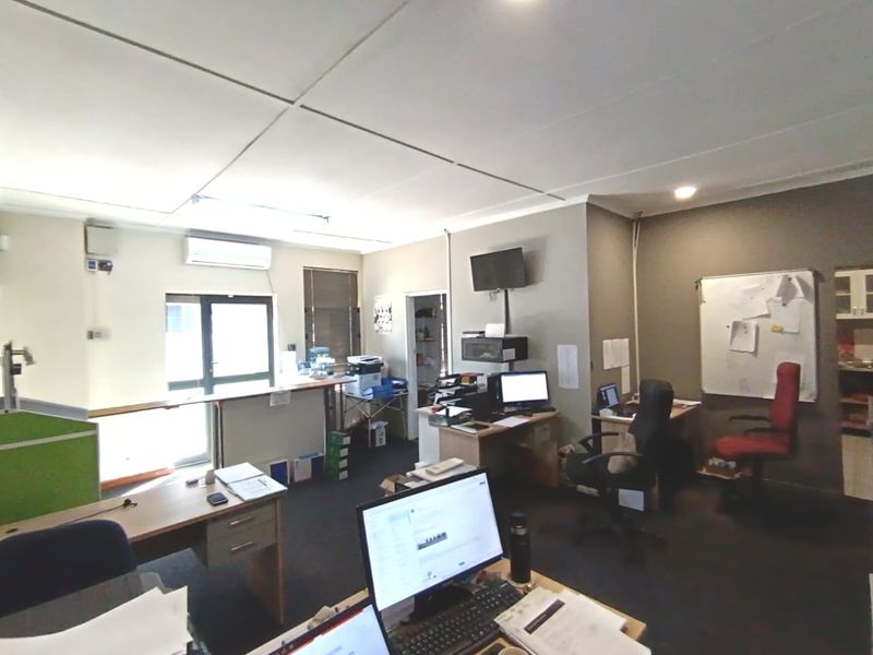 A functional commercial office space featuring a suspended ceiling, split-system air conditioning, and carpeted flooring, suitable for a professional work environment.