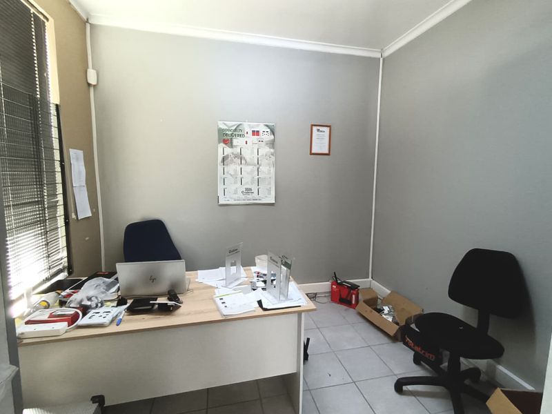 A functional office space featuring tiled flooring, coved ceilings, and window blinds, providing a practical environment for commercial operations.
