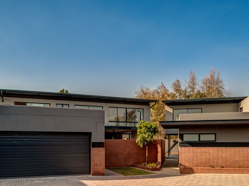 Modern residential property featuring a contemporary architectural design with a brick facade, flat roof, and a spacious paved driveway with double garage access.