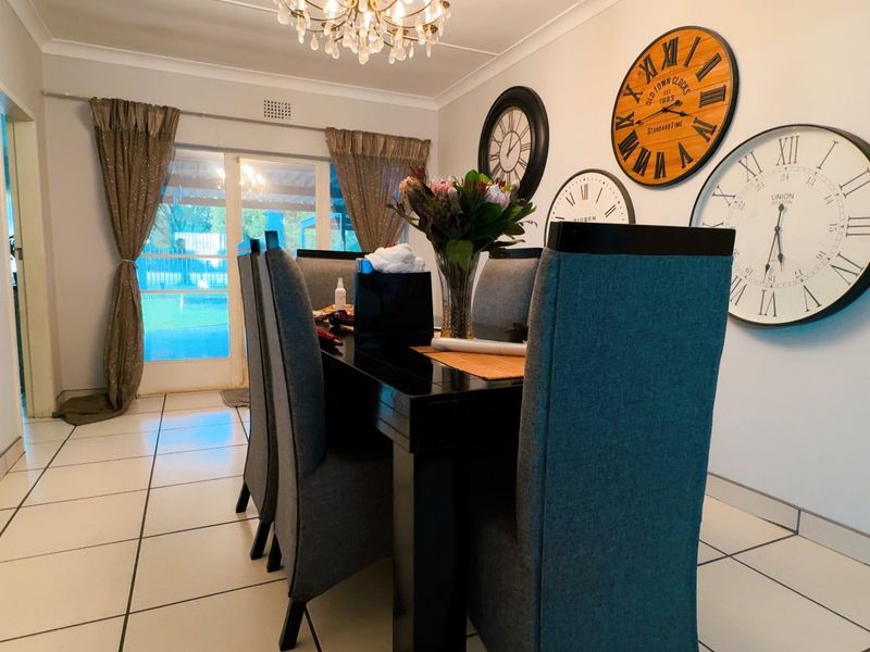 A well-lit dining room featuring tiled flooring, a crystal chandelier, and sliding glass doors providing access to the outdoor area.