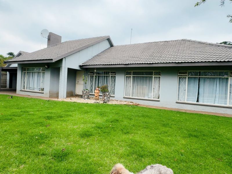 A single-story residential home featuring a tiled roof, brick chimney, and an attached carport, set on a well-maintained lawn.