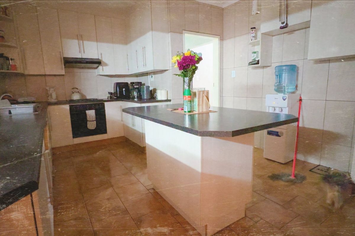 A functional kitchen featuring built-in cabinetry, a central island, tiled surfaces, and integrated appliances, offering a practical layout for daily meal preparation.