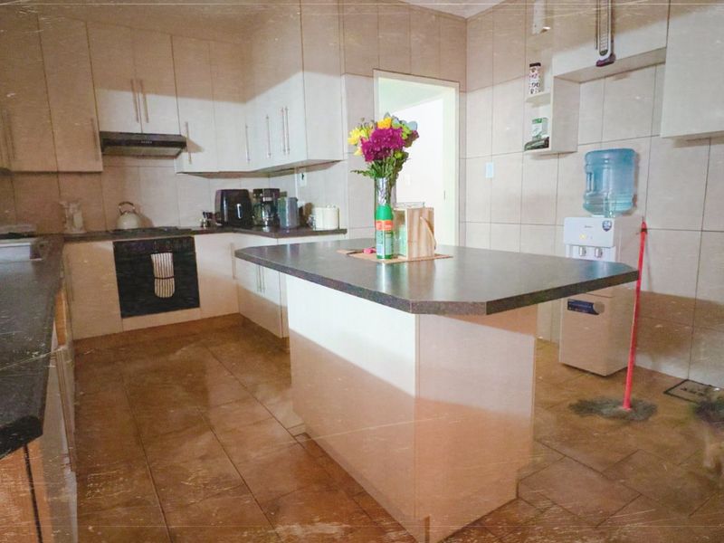 A functional kitchen featuring built-in cabinetry, a central island, tiled surfaces, and integrated appliances, offering a practical layout for daily meal preparation.