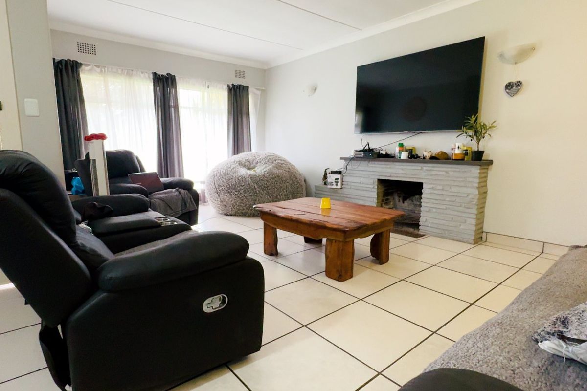 A living room featuring tiled flooring and a central brick fireplace, providing a functional space for relaxation.